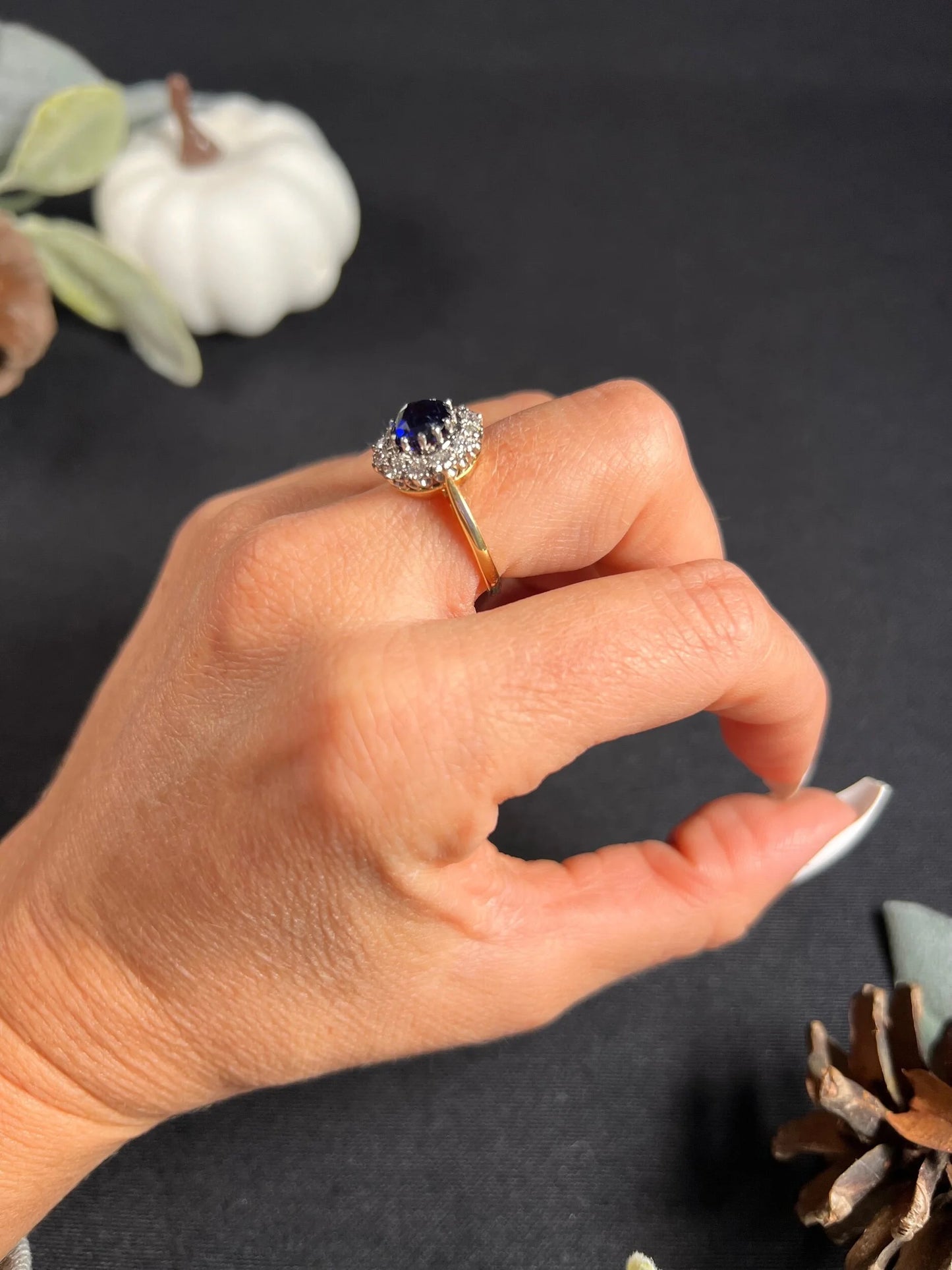 A round sapphire and diamond cluster ring, modelled on a hand