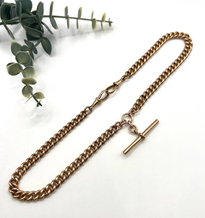 A rose gold curb link Albert chain on a white background