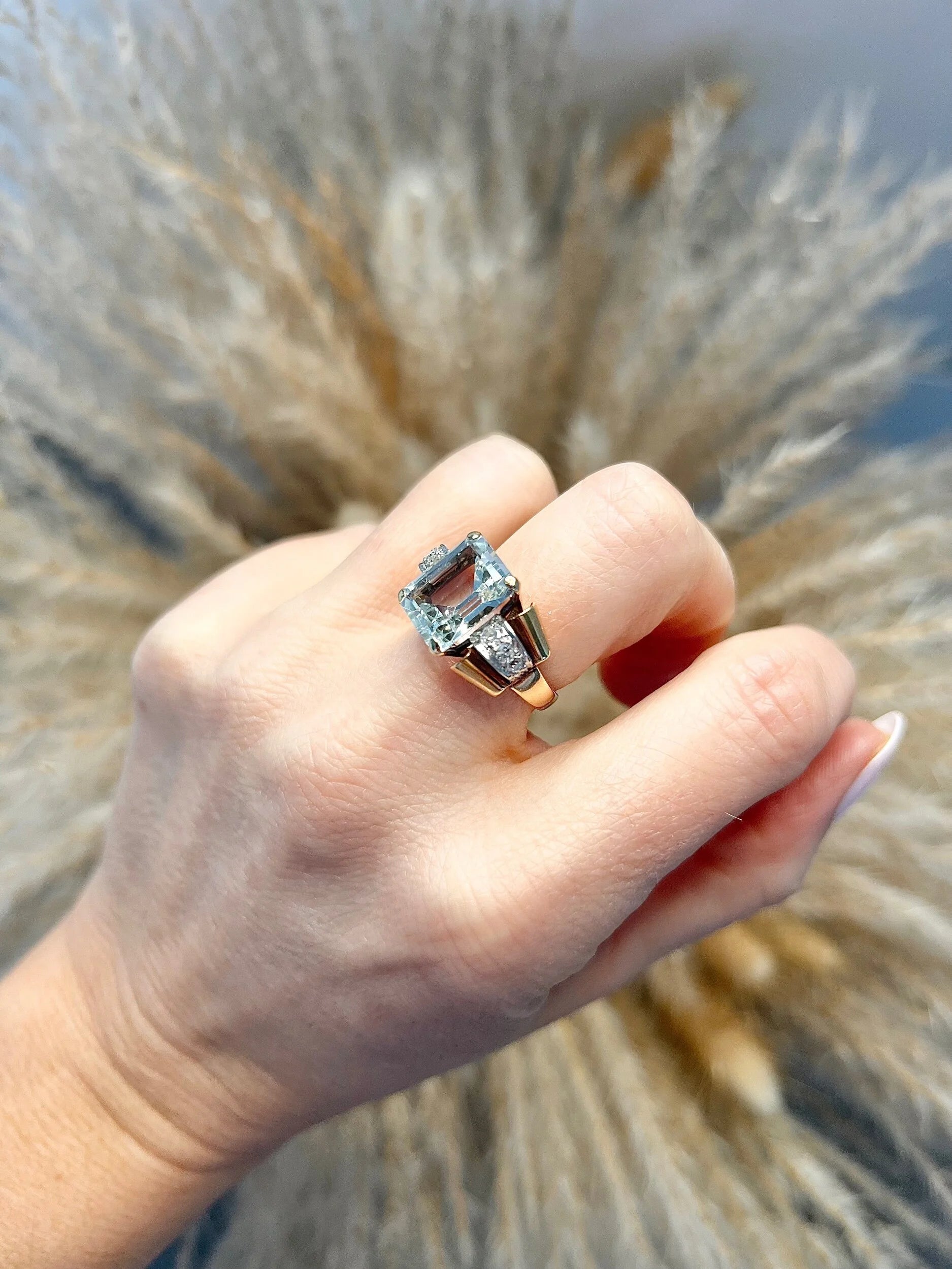 An aquamarine and diamond cocktail ring in gold, modelled on a hand