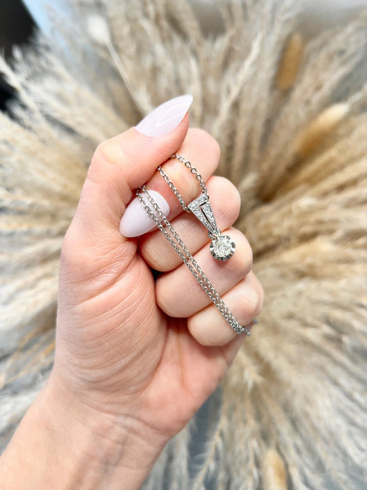 An old cut diamond pendant in white metal with a matching chain, held in a hand
