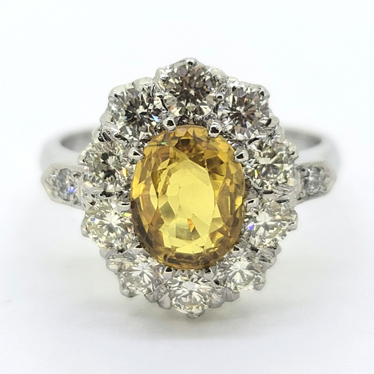 An oval yellow sapphire and round diamond cluster ring in platinum
