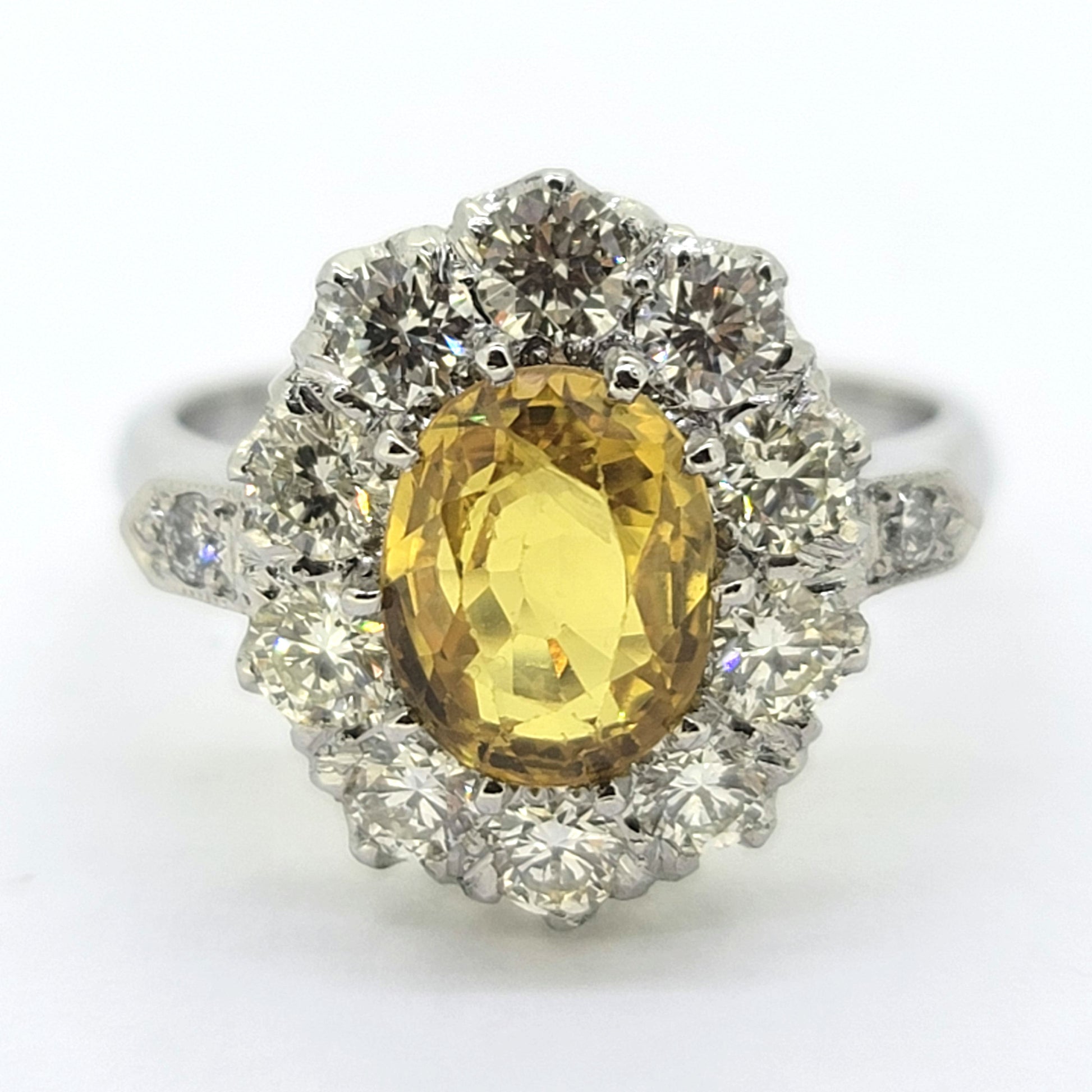 An oval yellow sapphire and round diamond cluster ring in platinum