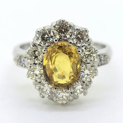An oval yellow sapphire and round diamond cluster ring in platinum