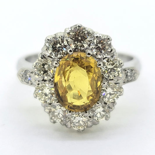 An oval yellow sapphire and round diamond cluster ring in platinum