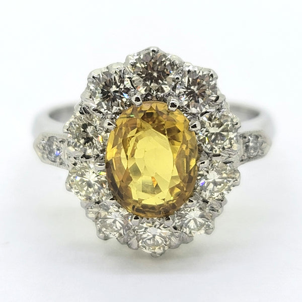 An oval yellow sapphire and round diamond cluster ring in platinum