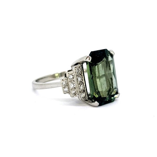 Art Deco Style 7.47ct Green Sapphire and Diamond Cocktail Ring; featuring a 7.47 carat emerald-cut green sapphire flanked by steps of pave set round brilliant-cut diamonds to each side, in platinum