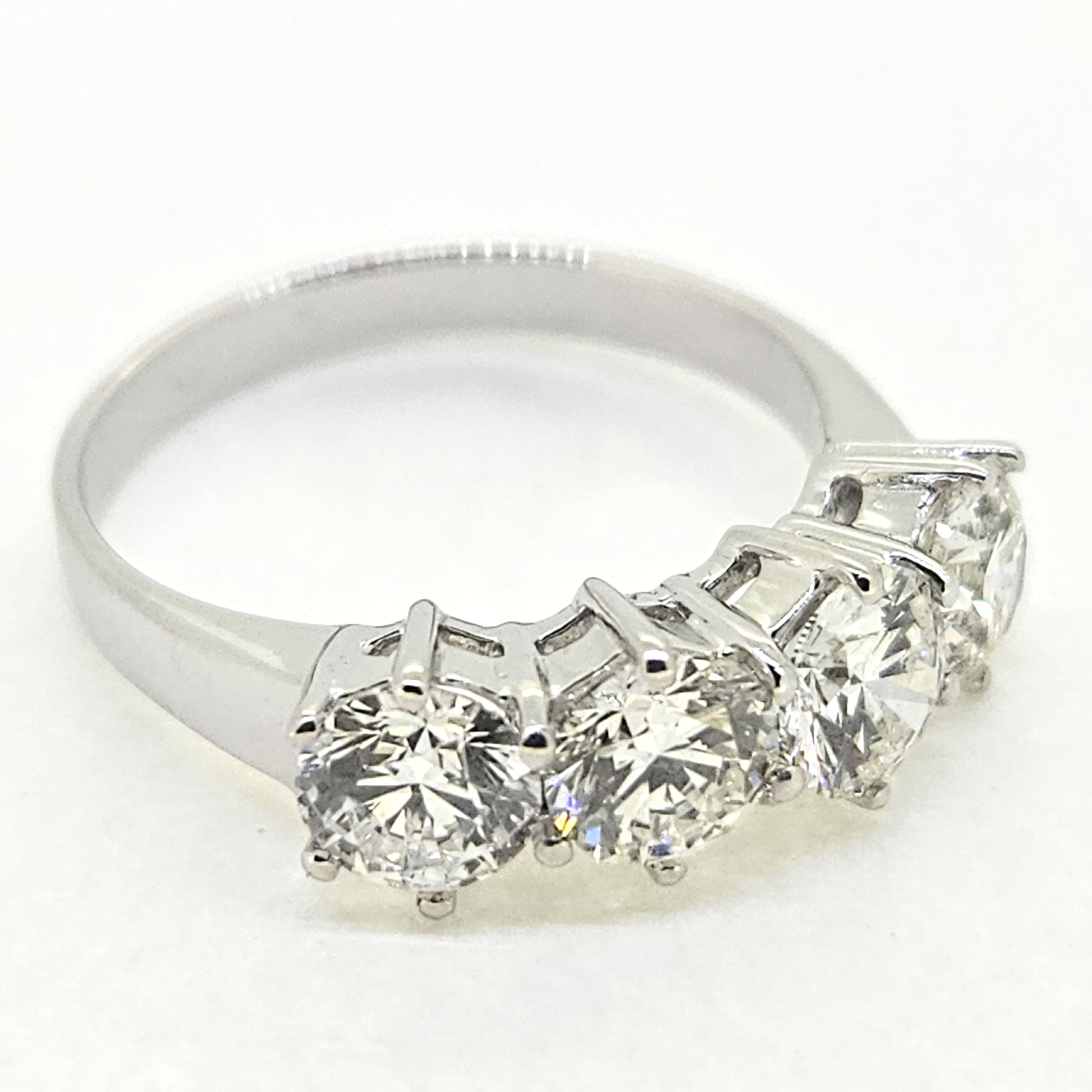 A four stone brilliant cut diamond ring in white gold, on a white background