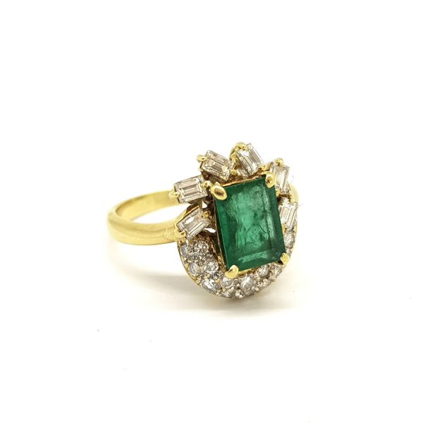 Vintage Emerald and Diamond Cluster Dress Ring; 2ct emerald-cut emerald surrounded by 1.20cts baguette and brilliant cut diamonds, in 18ct yellow gold