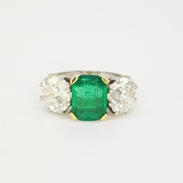 Colombian Emerald and Diamond Three Stone Ring; central certified 2.45ct emerald-cut Colombian emerald flanked by 4.56cts diamonds, in 18ct white gold