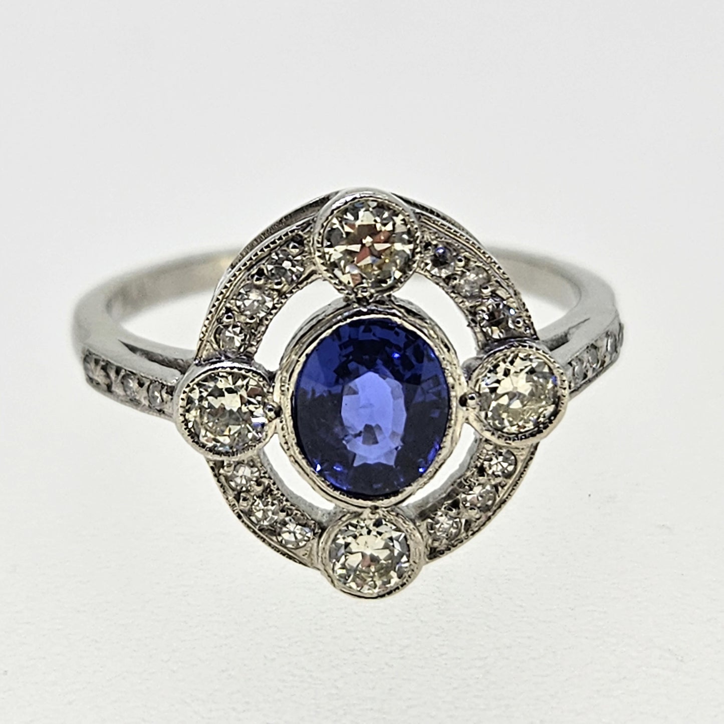 An oval sapphire and round diamond open cluster ring in platinum