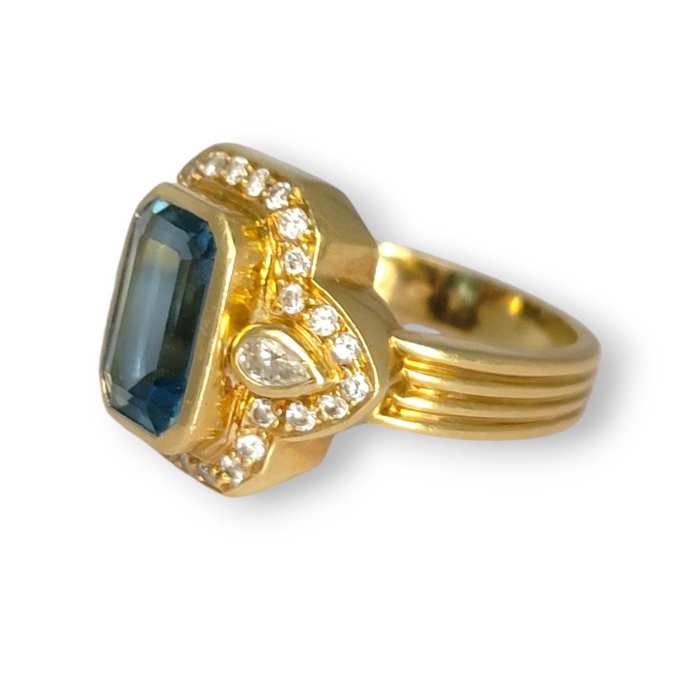 4.4ct Santa Maria Aquamarine and Diamond Cluster Dress Ring, 4.40ct emerald-cut Santa Maria aquamarine flanked by pear-cut diamonds all within diamond border in 18ct yellow gold