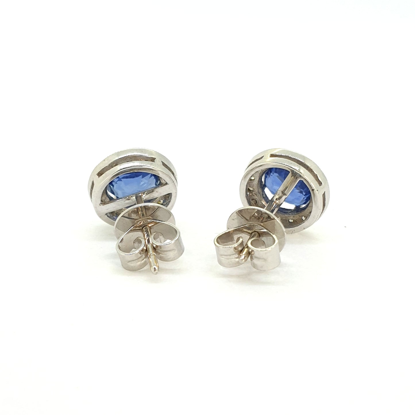 A pair of sapphire and diamond circular cluster earrings in white gold, on a white background