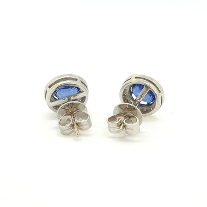 A pair of sapphire and diamond circular cluster earrings in white gold, on a white background
