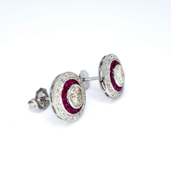 Calibre Ruby and Diamond Target Cluster Earrings; central brilliant-cut diamonds surrounded by calibre-cut rubies, all within outer diamond border, in 18ct white gold