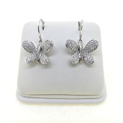 A pair of butterfly shaped diamond set earrings with hook fittings in white gold, on a white background
