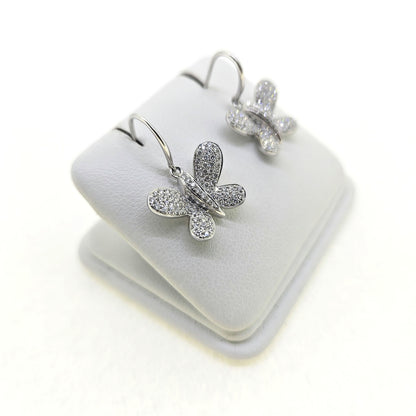 A pair of butterfly shaped diamond set earrings with hook fittings in white gold, on a white background