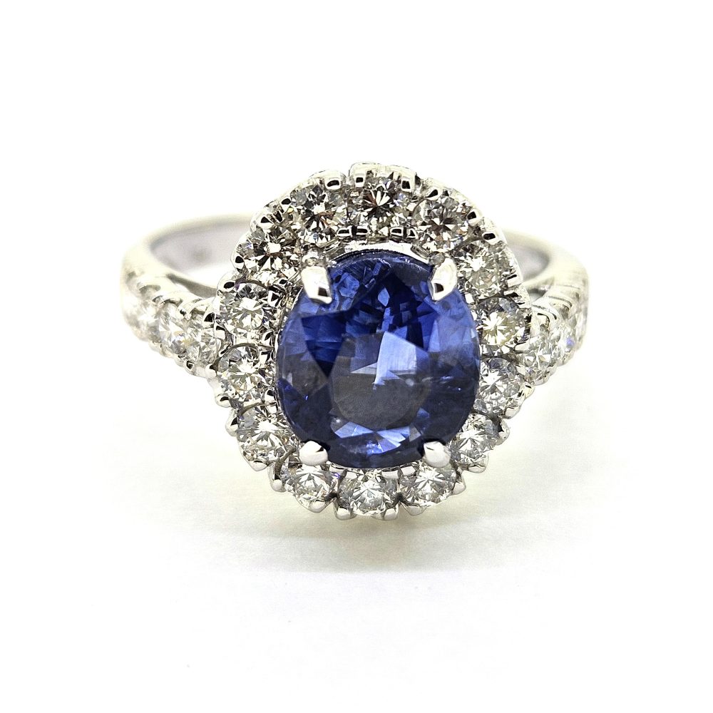 2.96ct Sapphire and Diamond Halo Cluster Engagement Ring in 18ct White Gold, 2.96ct blue sapphire surrounded by fixed halo border of sparkling diamonds with diamond shoulders