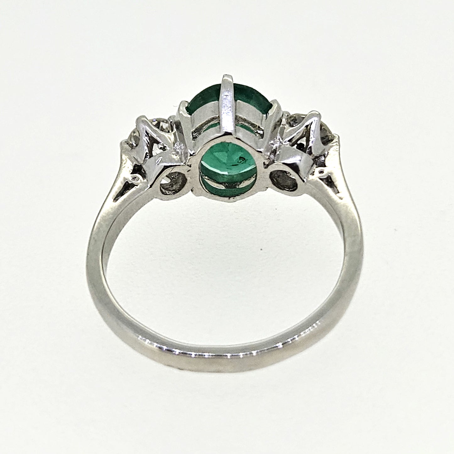 A three stone oval emerald and round diamond ring in platinum