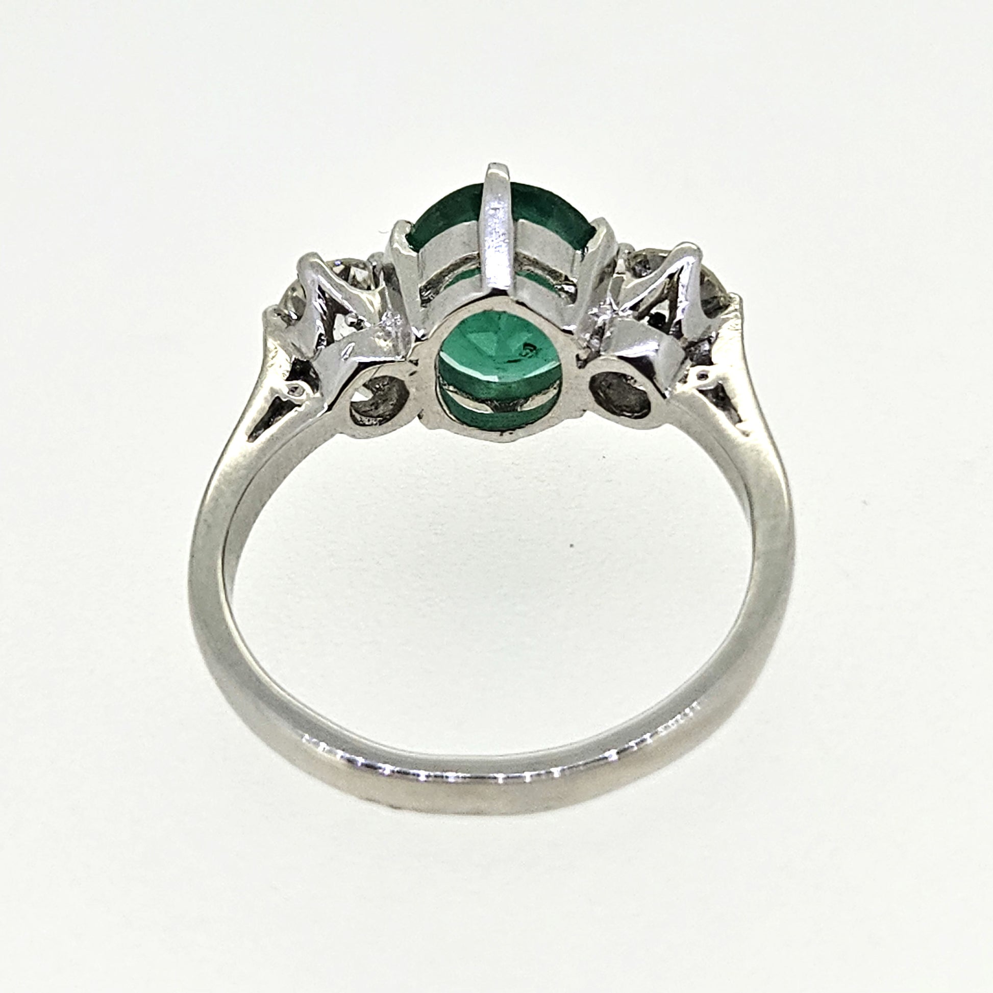 A three stone oval emerald and round diamond ring in platinum