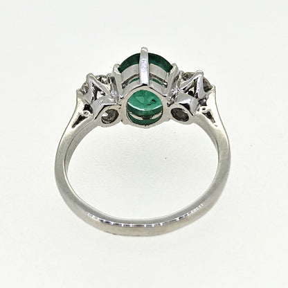 A three stone oval emerald and round diamond ring in platinum