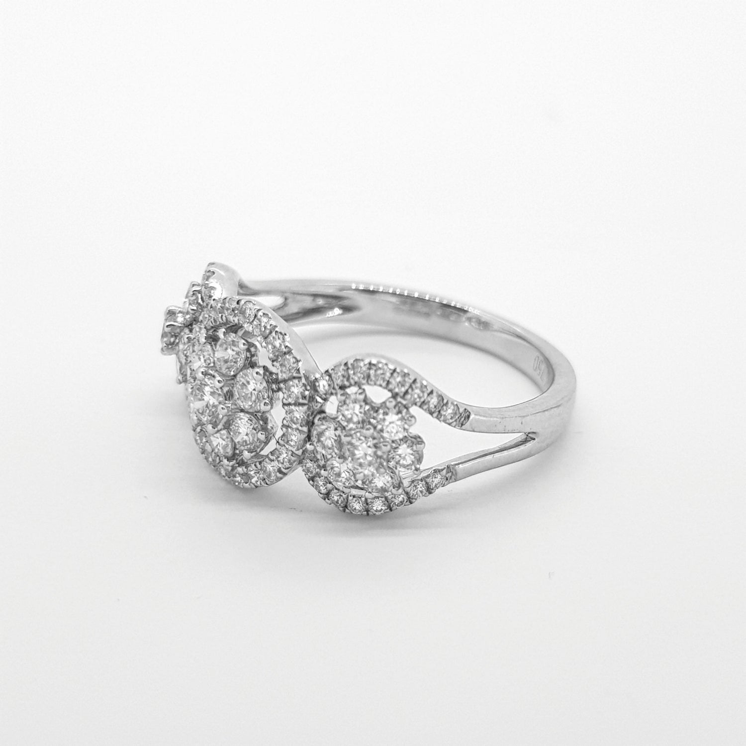 A circular triple cluster ring with round diamonds in white gold, against a white background