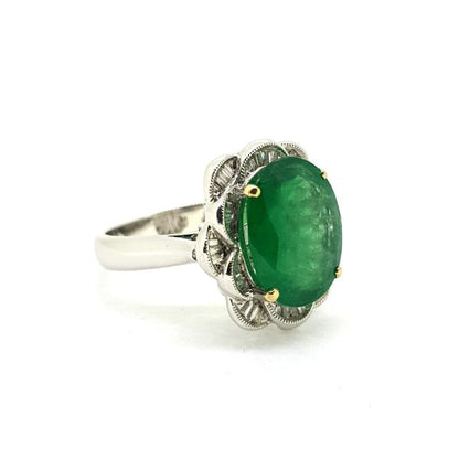 Emerald and Diamond Dress Ring; central 4.9ct oval faceted emerald surrounded by 0.57cts tapered baguette-cut diamond set into petal formation, in 18ct white gold