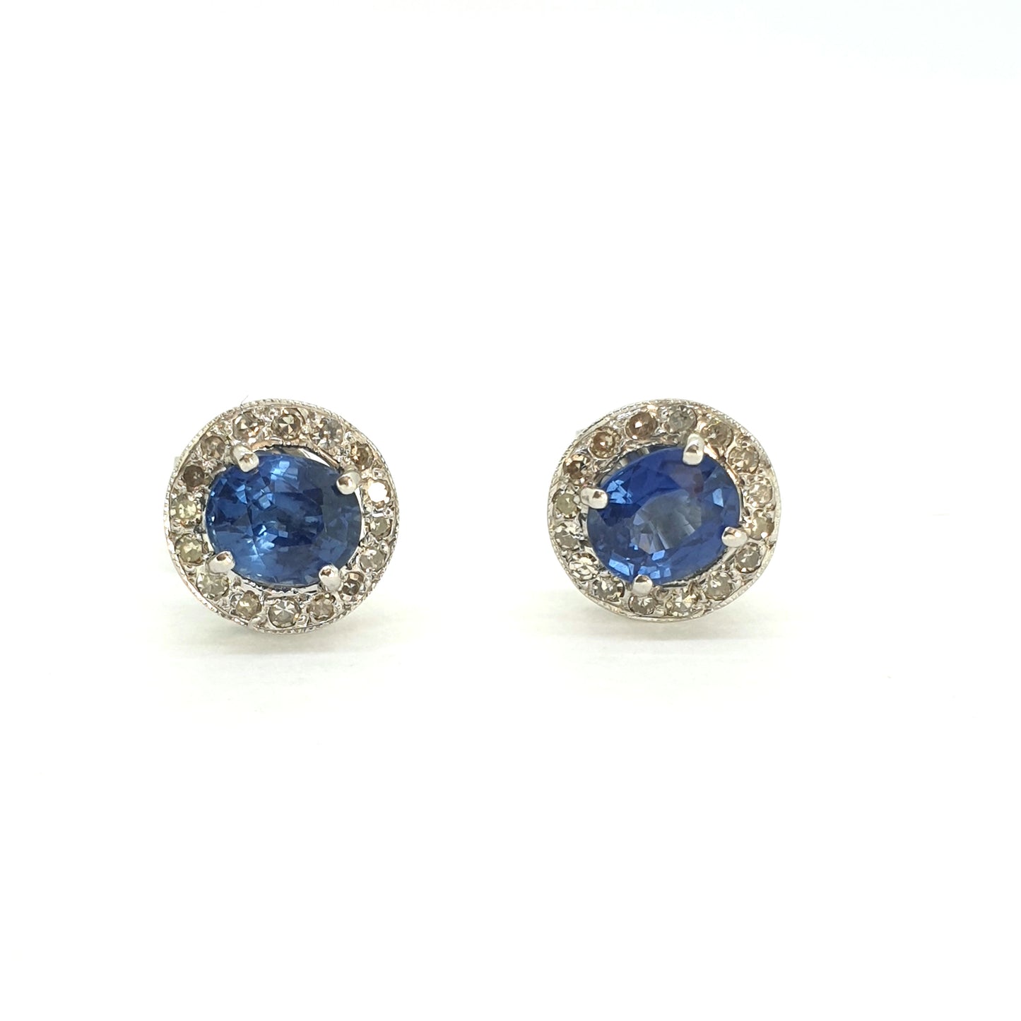 A pair of sapphire and diamond circular cluster earrings in white gold, on a white background