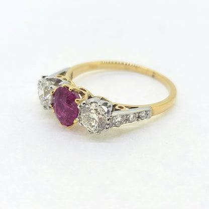 A three stone ruby and diamond ring in yellow and white gold, against a white background