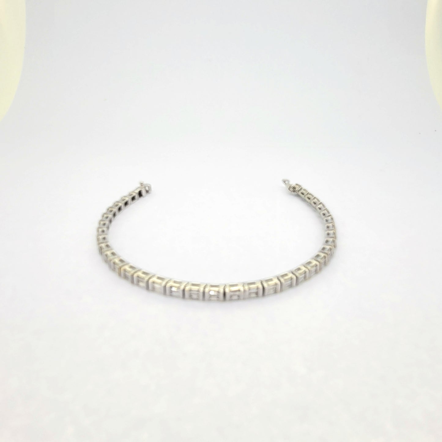 A baguette cut diamond line bracelet in white gold, against a white background