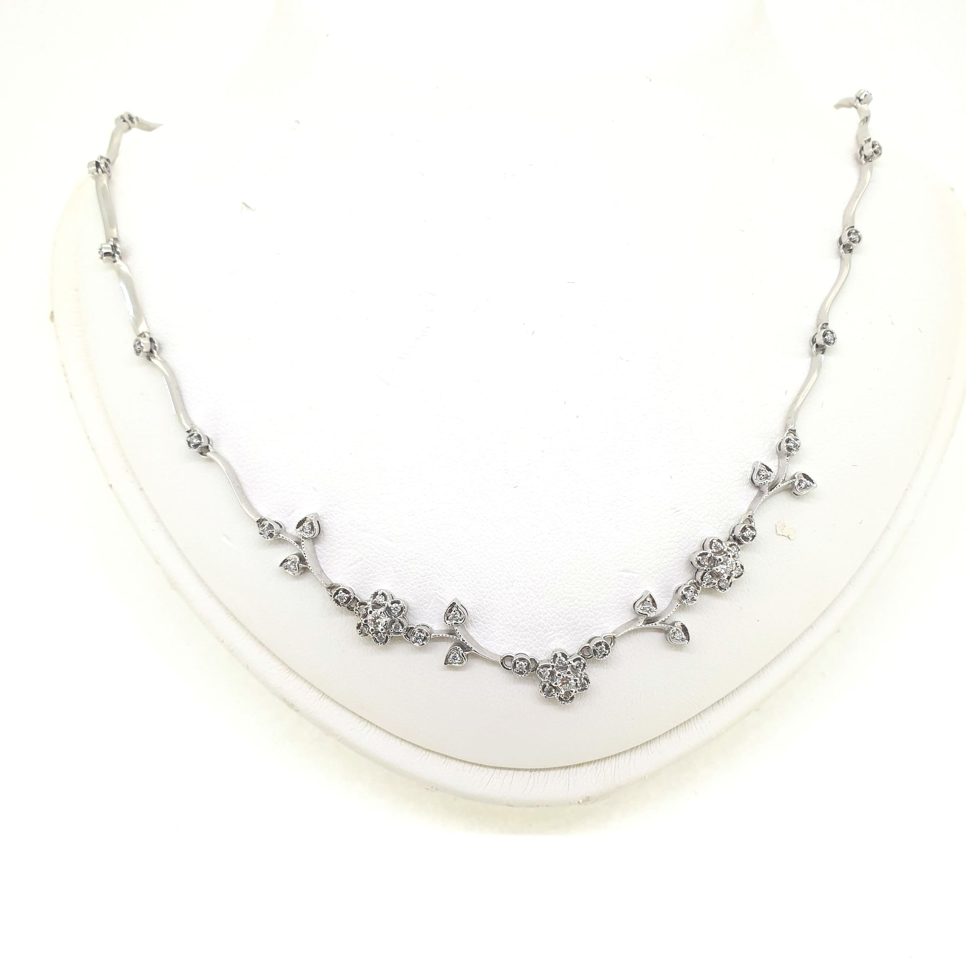 A floral diamond necklace in 14ct white gold, on a neck bust, on a white background
