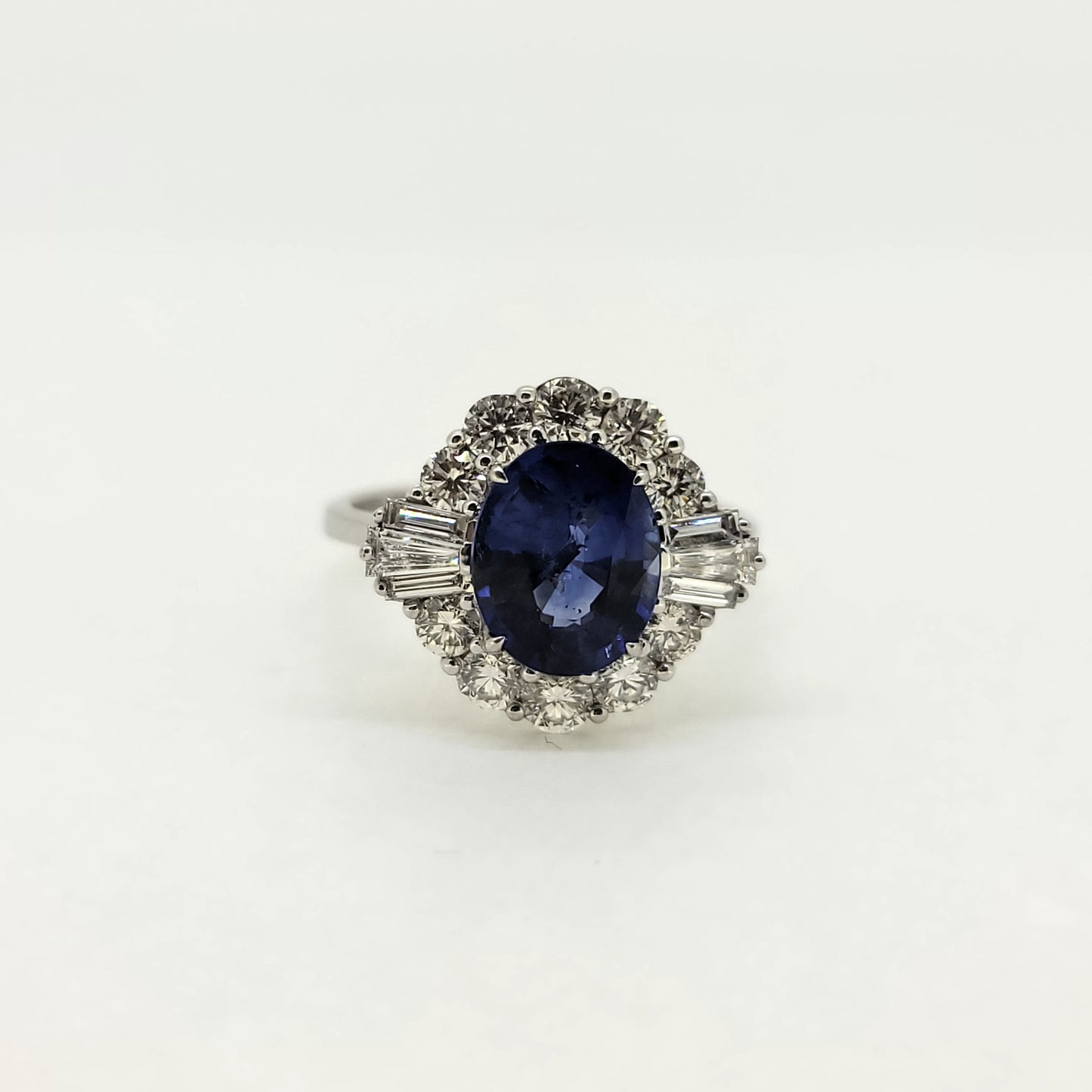 An oval sapphire, brilliant cut and baguette cut diamond cluster ring in white gold
