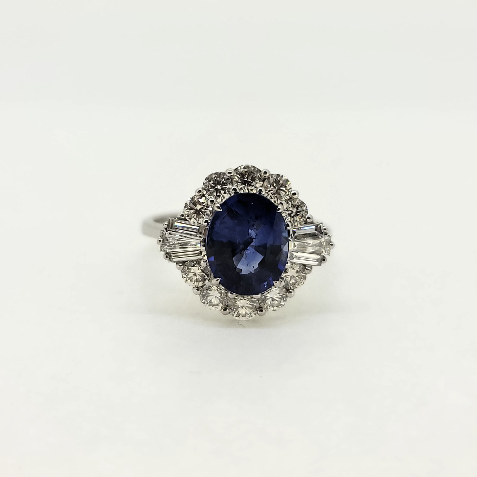 An oval sapphire, brilliant cut and baguette cut diamond cluster ring in white gold