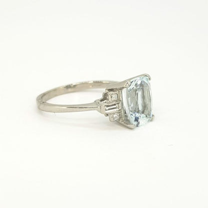 Aquamarine and Diamond Dress Ring in Platinum; central 2.20ct oval cushion-shaped aquamarine flanked by 0.20cts baguette-cut diamond set shoulders