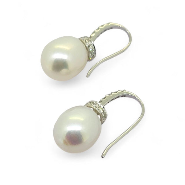 A pair of pearl and diamond drop earrings in white gold with hook fittings, against a white background