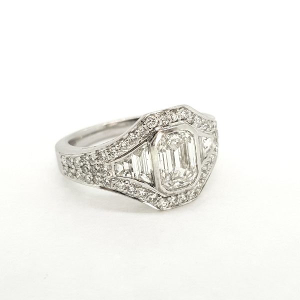 Contemporary Emerald Cut Diamond Cluster Ring; central GIA certified 1.22ct emerald-cut diamond is surrounded by brilliant and baguette-cut diamonds, in 18ct white gold, F colour, SI1 clarity
