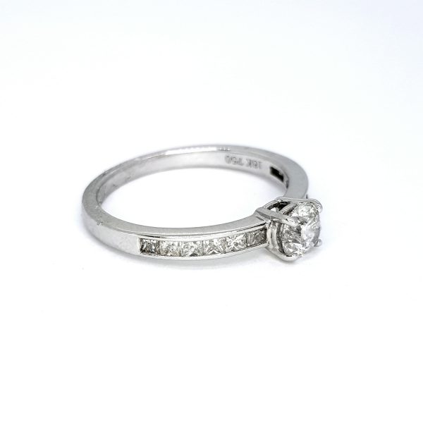 Diamond Solitaire Ring with Princess Cut Diamond Shoulders; central 0.51ct round brilliant-cut diamond, claw set and flanked by 0.43cts channel-set princess-cut diamond shoulders, in 18ct white gold