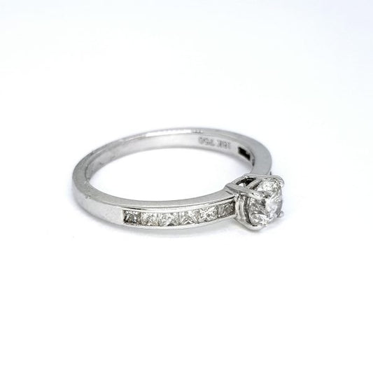 Diamond Solitaire Ring with Princess Cut Diamond Shoulders; central 0.51ct round brilliant-cut diamond, claw set and flanked by 0.43cts channel-set princess-cut diamond shoulders, in 18ct white gold