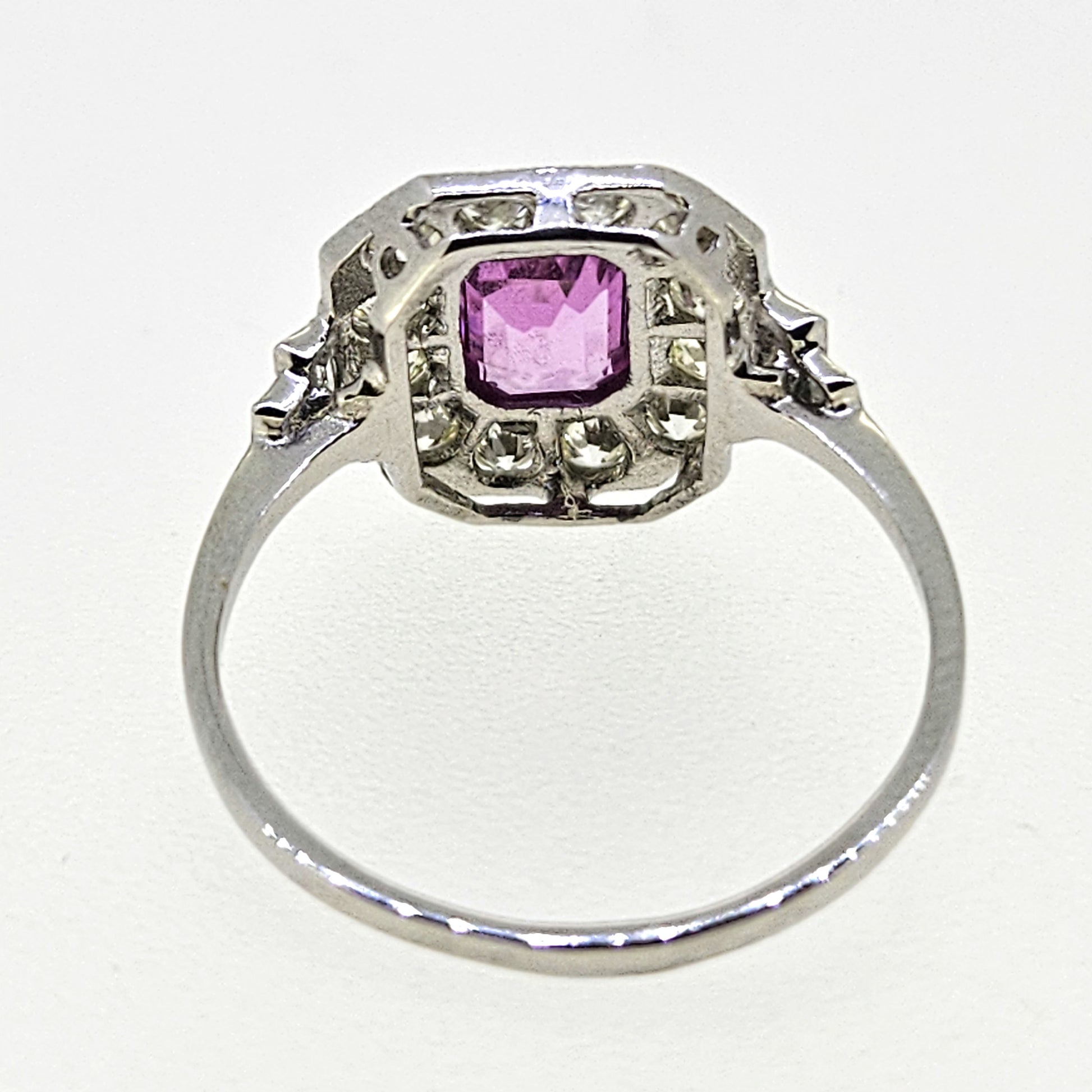 An emerald cut pink sapphire and diamond cluster ring in platinum