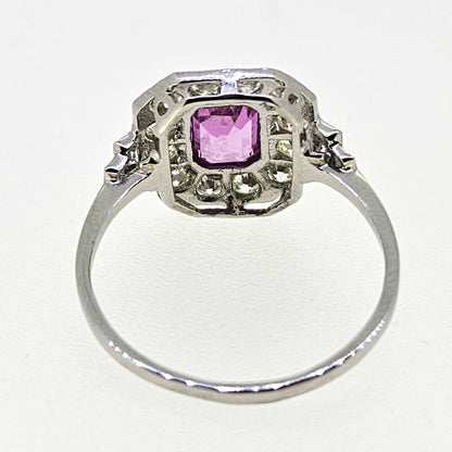 An emerald cut pink sapphire and diamond cluster ring in platinum