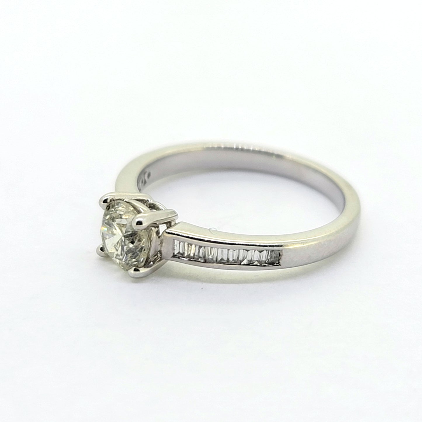 A brilliant and baguette cut diamond ring in white gold, against a white background