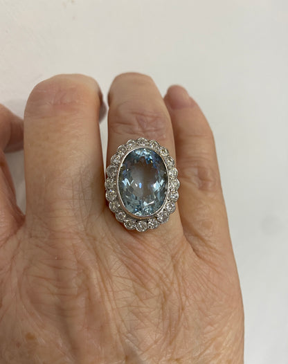 An aquamarine and diamond oval shaped cluster ring in yellow and white gold, modelled on a ring finger