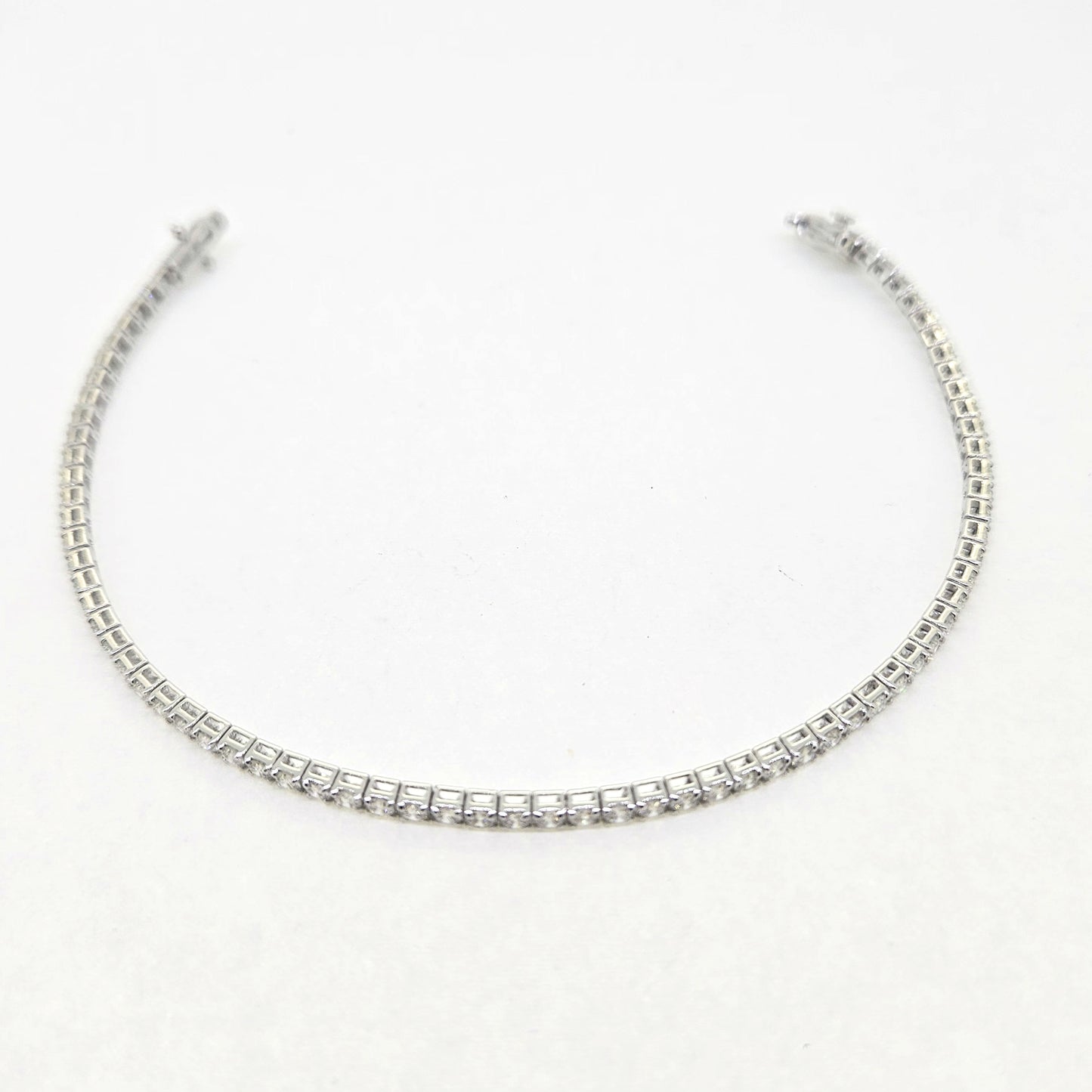 A brilliant cut diamond line bracelet, clasp open, on a white background