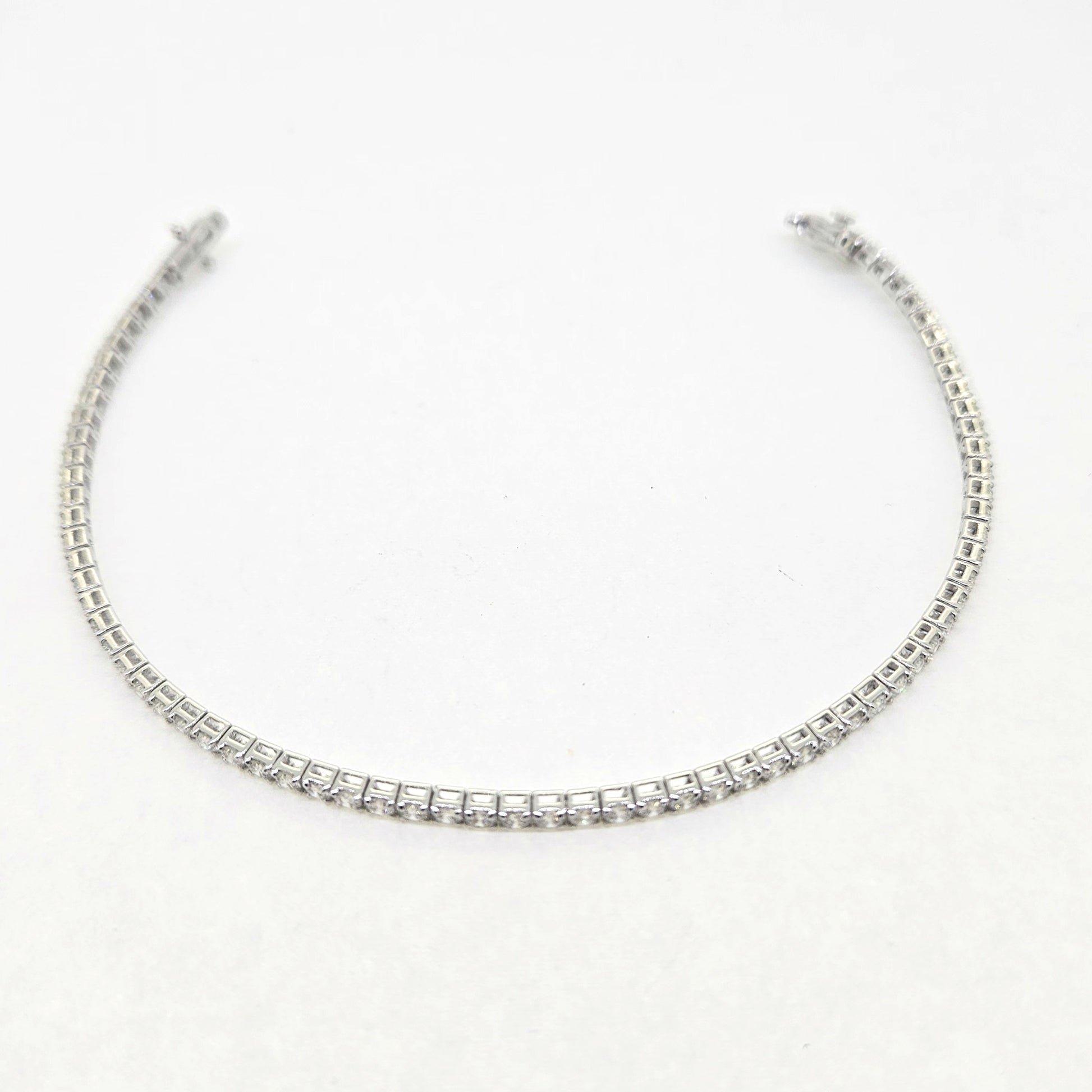 A brilliant cut diamond line bracelet, clasp open, on a white background