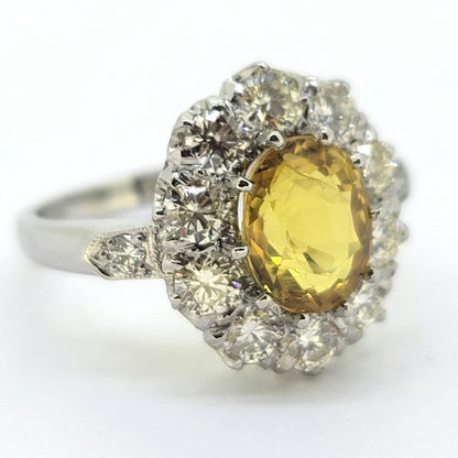 An oval yellow sapphire and round diamond cluster ring in platinum