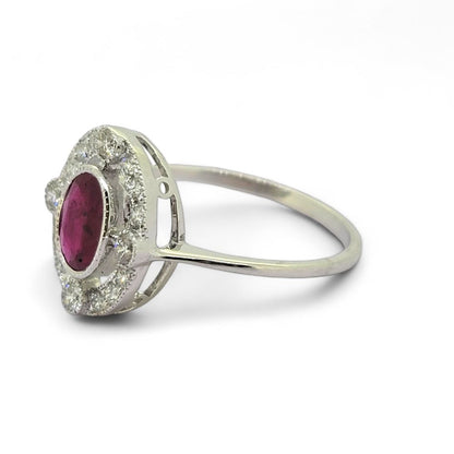 Ruby and Diamond Halo Cluster Engagement Ring, 0.70ct oval red ruby surrounded by fixed halo of diamonds with larger diamonds at the four compass points in 18ct white gold