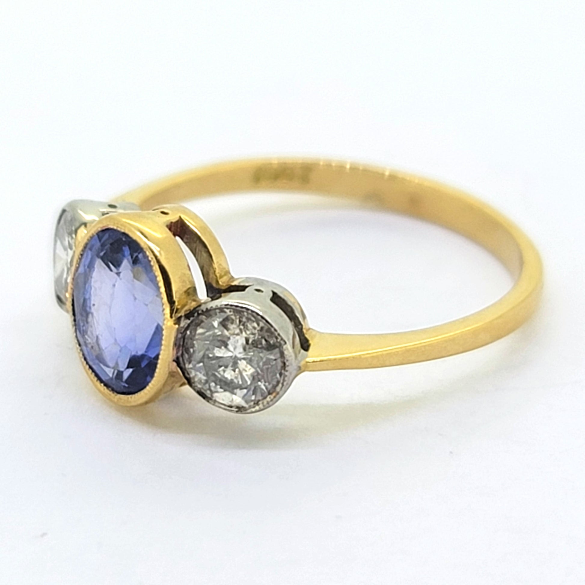 A three stone sapphire and diamond ring in yellow and white gold, on a white background