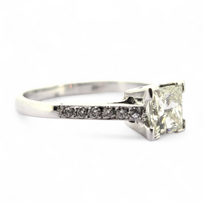 A princess cut diamond solitaire ring with diamond shoulders, in white gold, on a white background