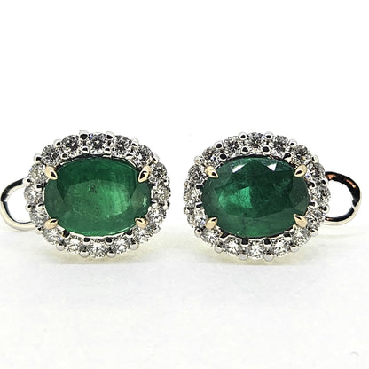 A pair of emerald and diamond oval cluster earrings in white gold, on a white background