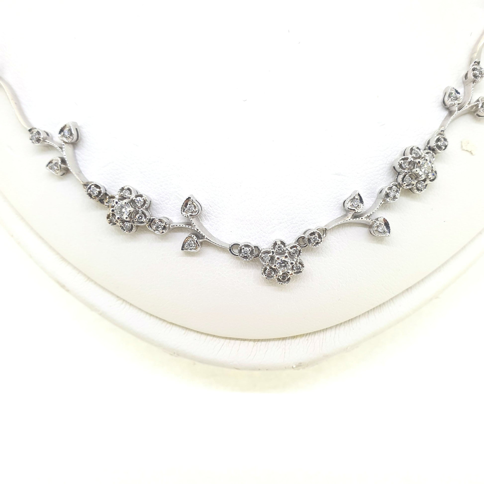 A floral diamond necklace in 14ct white gold, on a neck bust, on a white background