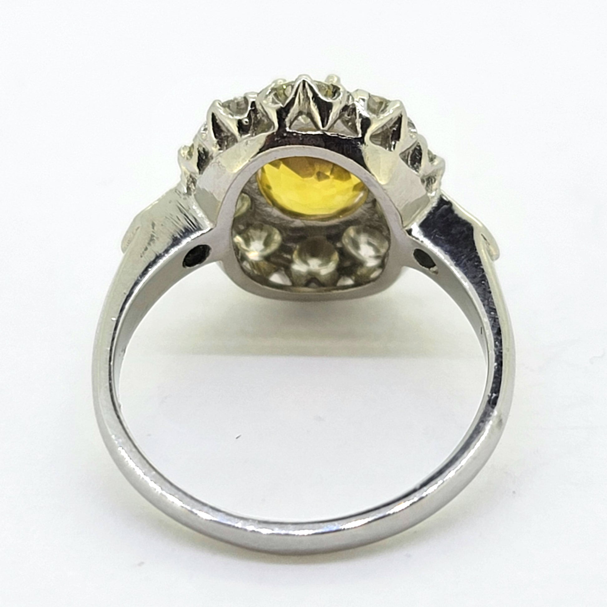 An oval yellow sapphire and round diamond cluster ring in platinum